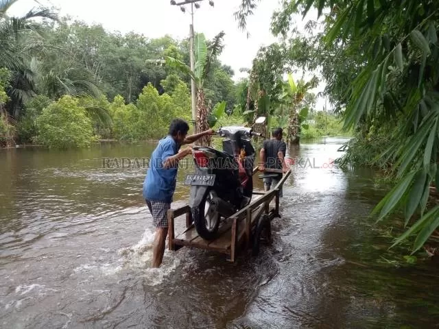 LEWATI BANJIR: Seorang pria membawa sepeda motor melewati genangan air di Tabalong, belum lama tadi. Tabalong menjadi salah satu dari sepuluh dari yang rawan banjir di Kalsel. | FOTO: DOK/RADAR BANJARMASIN
