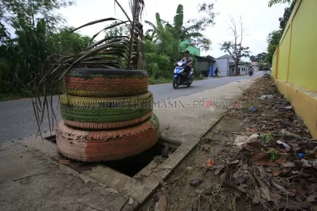 DIGONDOL MALING: Sejumlah tutup drainase di Jalan Batas Kota atau tepatnya di depan SDN 1 Sungai Ulin Banjarbaru raib. Karena berbahaya bagi pengendara, lubang menganga ditutup dengan ban bekas. | Foto: Muhammad Rifani/Radar Banjarmasin