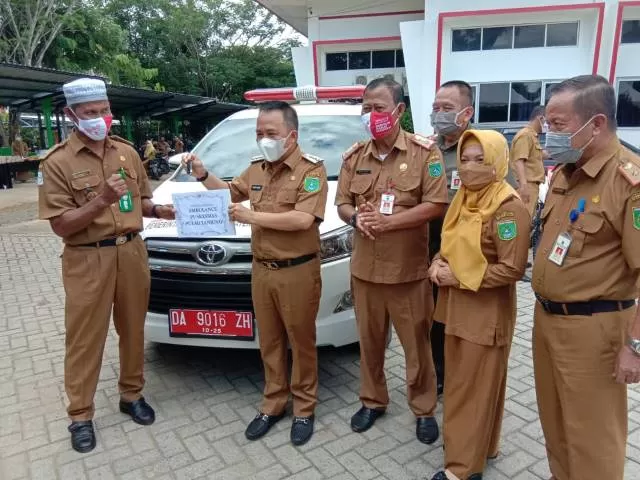 MENYERAHKAN: Dalam syukuran HKN ke-56, bupati menyerahkan 1 unit mobil ambulans bagi Puskesmas Pulau Tanjung Kecamatan Kusan Hilir dan 1 unit motor.