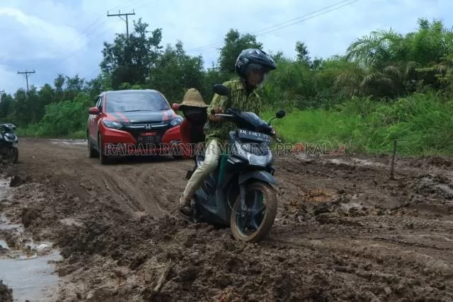 DORONG: Salah satu warga membantu mendorong sepeda motor pengguna jalan yang melintasi ruas jalan Margasari-Marabahan di Kecamatan Candi Laras Utara. | Foto: Rasidi Fadli/Radar Banjarmasin