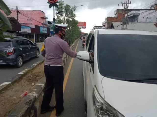 PELAN SAJA: Kasatlantas Polres Tanah Bumbu memberikan selebaran panduan berkendara kepada warga di pusat kota di daerah ini, Rabu (13/1) kemarin.