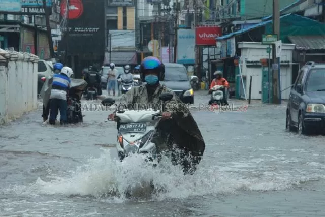 HAMPIR SEDENGKUL: Pengendara menerobos banjir di Jalan Cemara, kemarin (14/1) sore. Banyak motor yang kemogokan. | FOTO: WAHYU RAMADHAN/RADAR BANJARMASIN