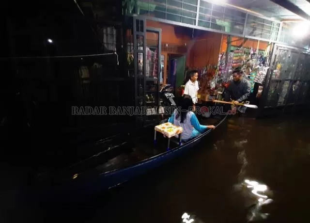 PAKAI JUKUNG: Jukung kembali menjadi andalan warga Banjarmasin selama banjir. Dalam foto ini, warga Sungai Lulut berbelanja ke warung dengan mengayuh sampan. | FOTO: WAHYU RAMADHAN/RADAR BANJARMASIN