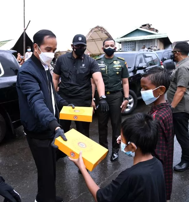 BAGI DONAT: Presiden RI Joko Widodo berbagi makanan kepada anak-anak saat mengunjungi Kabupaten Banjar, salah satu daerah yang terdampak banjir paling besar di Kalsel, kemarin (18/1). | FOTO: SETPERS FOR RADAR BANJARMASIN