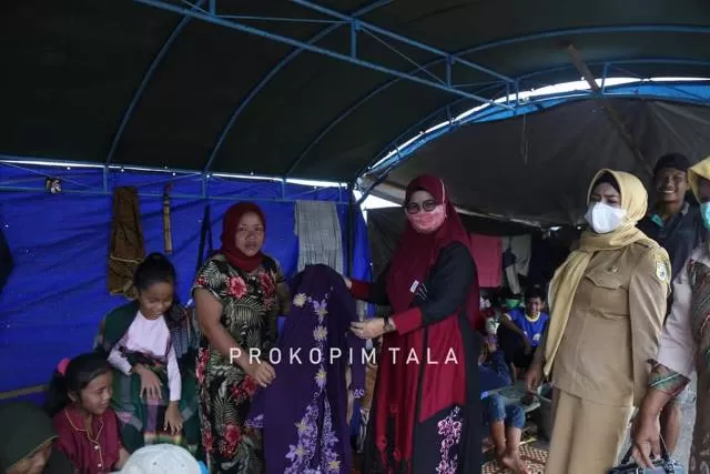 SEMANGAT: Ketua TP PKK Tala Hj Nurul Sukamta mendatangi tenda-tenda pengungsi sembari membawakan bantuan.