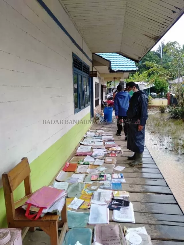 BAKSOS : Plt Kadisdik Balangan, Abdul Basyid (kiri) saat melihat kondisi buku-buku sekolah yang rusak terdampak banjir. | FOTO: WAHYUDI/RADAR BANJARMASIN.