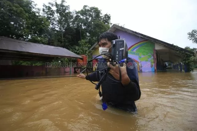 SELAMATKAN: Salah seorang guru di SDN 2 Bangkal menyelamatkan peralatan elektronik milik sekolah ketika banjir beberapa waktu lalu. Akibat banjir, belasan sekolah terdampak ringan hingga sedang.| Foto: Muhammad Rifani/Radar Banjarmasin