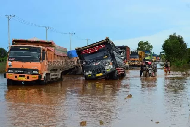 MUATAN BERAT: Truk-truk bermuatan yang terperosok kubangan lumpur di Jalan Gubernur Syarkawi, Sabtu (6/2) lalu. Meski pernah diperbaiki, jalanan selalu rusak karena tak ada pemeriksaan beban angkutan yang melintas. | FOTO: WAHYU RAMADHAN/RADAR BANJARMASIN