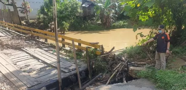 RUSAK BERAT: Kondisi jembatan di Desa Kaong yang rusak diperlihatkan Camat Upau, Rofik.