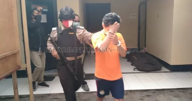 SISA PENYESALAN: Pelaku menutupi mukanya ketika dihadirkan di gelar kasus di Polsek Banjarmasin Utara. | FOTO: MAULANA/RADAR BANJARMASIN