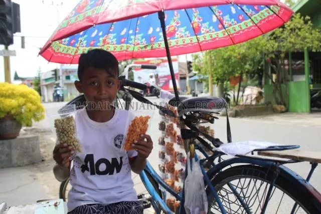 SEMANGAT: M Ramadani semangat berjualan cemilan kacang-kacangan untuk meringankan beban orang tuanya. Dani juga ingin membeli gadget dari hasil penjualan tersebut agar bisa ikut sekolah daring. | Foto: Jamaluddin/Radar Banjarmasin