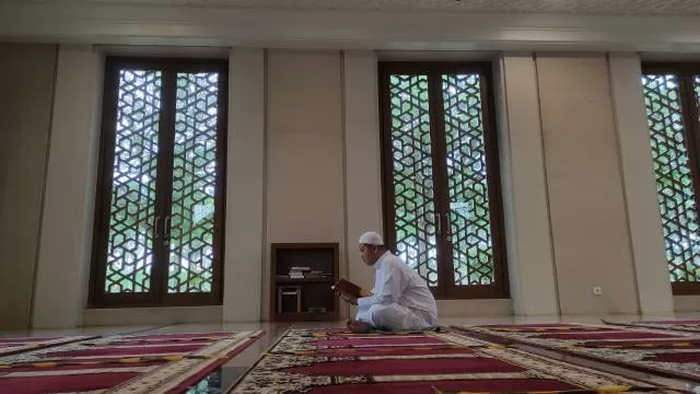 IBADAH: Ilyas mengaji di sudut masjid. Selama Ramadan dia menyempatkan diri memperbanyak ibadah, salah satunya memperlancar bacaan mengajinya