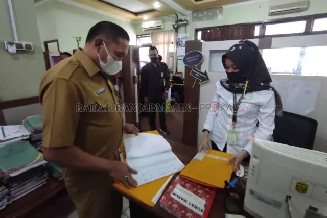 INSPEKSI MENDADAK: Plh Sekdako Banjarmasin, Mukhyar mengecek daftar absensi pegawai pemko, (17/5). | FOTO: WAHYU RAMADHAN/RADAR BANJARMASIN