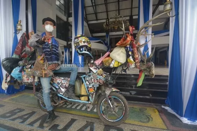 BANYAK CENDERAMATA: M Hanif Kusuma berpose dengan motor yang dia pakai berkeliling Indonesia di depan balaikota Banjarmasin. | FOTO: WAHYU RAMADHAN/RADAR BANJARMASIN