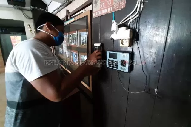 SIDIK JARI: Pegawai pemko mengisi ulang hand sanitizer di samping alat absen sidik jari Balai Kota di Jalan RE Martadinata. | FOTO: WAHYU RAMADHAN/RADAR BANJARMASIN