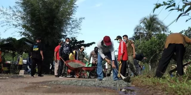KEBERSAMAAN: Warga Kintap bersama Bupati Tala HM Sukamta gotong royong menutup lubang jalan.