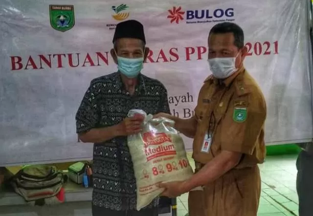 PEDULI: Kadinsos Tanah Bumbu Basuni membagikan paket beras PPKM kepada warga yang berhak.