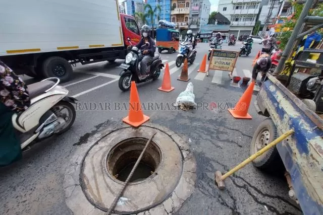 BERBAHAYA: Tutup manhole milik PDAM yang hilang di pertigaan Jalan Kol Sugiono. Kemarin (23/7), pekerja PDAM mulai memperbaikinya. | FOTO: WAHYU RAMADHAN/RADAR BANJARMASIN