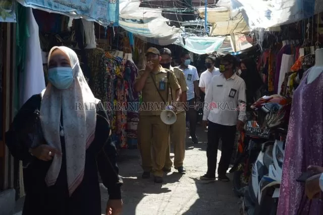 SERUKAN PPKM: Petugas Disperdagin Banjarmasin meminta pedagang dan pembeli di Pasar Sudimampir untuk mengenakan masker, kemarin (26/7). | FOTO: WAHYU RAMADHAN/RADAR BANJARMASIN
