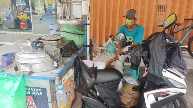KENA DAMPAK: Adi saat menjaga dagangan pentolnya di depan mini market di Jalan Trikora Guntung Lua, Kelurahan Loktabat Utara, kemarin. Selama PPKM, penjualannya turun signifikan. | FOTO: SUTRISNO/RADAR BANJARMASIN