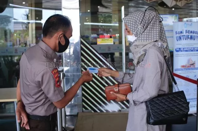 DIPERIKSA: Petugas keamanan Q Mall Banjarbaru melihat kartu vaksin salah seorang calon pengunjung sebelum masuk ke area mal sebagai salah satu syarat - Foto: Muhammad Rifani/Radar Banjarmasin
