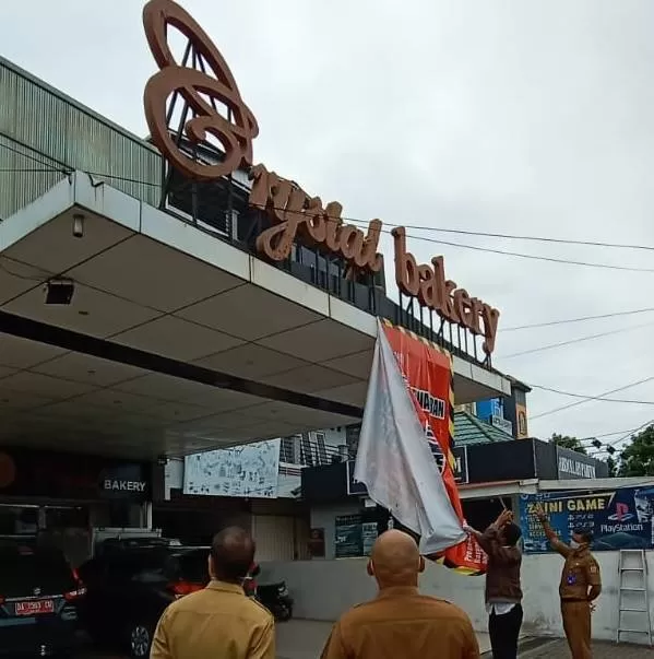 DILEPAS: Petugas BPPRD Kota Banjarbaru melepas spanduk terkait sengketa obyek pajak toko roti di Banjarbaru, setelah polemik ini tuntas. | Foto: BPPRD Banjarbaru for Radar Banjarmasin