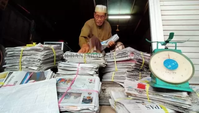ERA SENJA: Haji Abdul Syukur bersama tumpukan koran bekasnya. Agennya berada di Jalan Pangeran Samudera Gang Penatu, Banjarmasin Tengah. | FOTO: ENDANG SYARIFUDDIN/RADAR BANJARMASIN