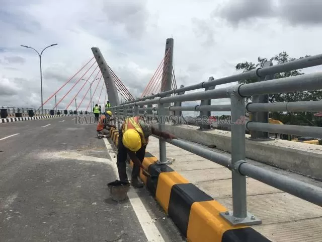 FINISHING: Pekerja dari Wika-Pandji mengecat trotoar Jembatan Sungai Alalak, kemarin. Pekerjaan jembatan akan berakhir 15 September mendatang.  | FOTO: M OSCAR FRABY/RADAR BANJARMASIN