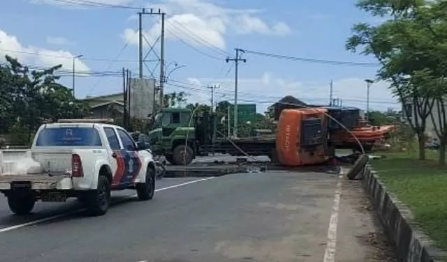 TERBALIK: Truk tronton pengangkut alat berat yang menabrak median jalan di kawasan Trikora Banjarbaru.