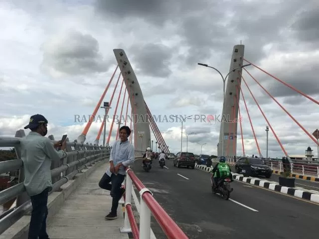 SUDUT BAGUS: Warga berpose di jembatan Sungai Alalak yang dibuka kemarin sore. Desakan warga mendapat perhatian pemerintah pusat yang langsung menyuruh otoritas setempat untuk membuka jembatan. | FOTO: M OSCAR FRABY/RADAR BANJARMASIN