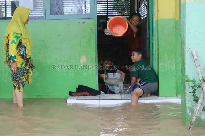 BANJIR: Murid salah satu sekolah di Tapin membuang air dari kelasnya, beberapa waktu lau. Untuk mengantisipasi banjir BPBD Tapin, akan melakukan langkah mitigasi.