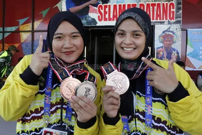 BERHASIL: Annisa (kiri) dan Nur Cahaya (kanan) memamerkan seluruh medali yang mereka persembahkan untuk Kalsel dalam ajang PON XX 2021 Papua. | DOC.