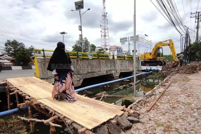 SEADANYA: Seorang warga Kompleks Pandu melintasi jembatan darurat yang dibangun. Warga protes, lantaran jembatan darurat ini dituding bisa membahayakan warga. | FOTO: WAHYU RAMADHAN/RADAR BANJARMASIN