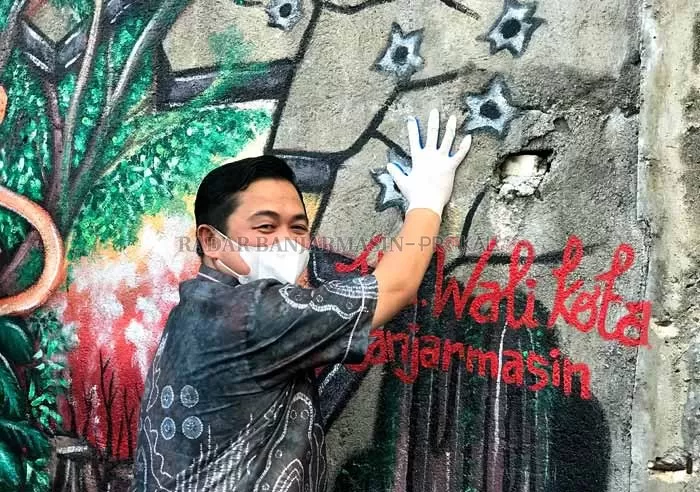 BERI DUKUNGAN: Wali Kota Banjarmasin Ibnu Sina membubuhkan cap tangan di dinding bangunan berhias mural di kawasan The Jumpa Square, yang menjadi tempat penutupan gelaran BMF 2021. | Foto: Wahyu Ramadhan / Radar Banjrmasin