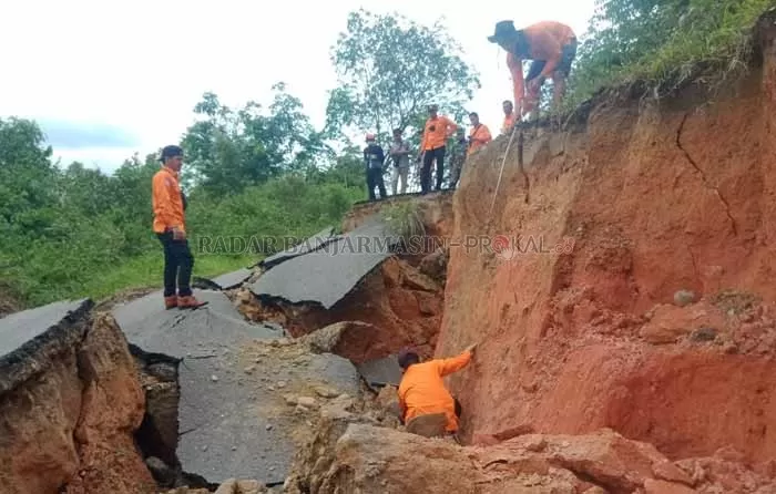 UKUR LONGSOR: Anggota BPBD Tapin mengukur ketinggian longsor di Jalan Desa Tatakan Kecamatan Tapin Selatan arah wisata religi makam Datu Nuraya.