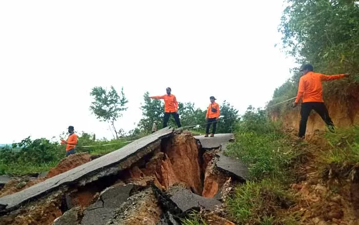 UKUR LONGSOR: Anggota BPBD Kabupaten Tapin mengukur jalan yang longsor di Desa Tatakan Kecamatan Tapin Selatan dekat makam Datu Nuraya.