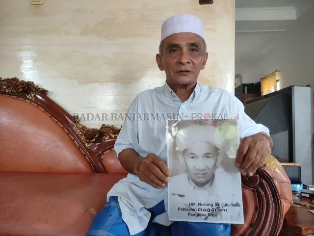 KENANGAN KELUARGA: Haji Muhdar memegang foto kakeknya Haji Muhammad Nurung, tokoh agama yang bertempur membela kota Pagatan. | FOTO: ZALYAN SHODIQIN ABDI/RADAR BANJARMASIN