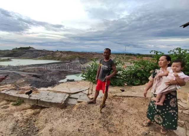DI TEPI TAMBANG: Jumadi dan tetangganya Suharti berdiri di tepi lubang tambang Desa Banjarsari Kecamatan Angsana. Tampak sisa kamar mandi Jumadi yang rusak akibat longsor. | FOTO: ZALYAN SHODIQIN ABDI/RADAR BANJARMASIN