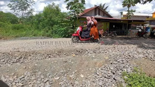 BELUM ASPAL: Warga melintas di  sebuah jalan yang masih pengerasan di Tanah Bumbu. Banyak daerah masih suka endapkan dana pembangunan fisik.