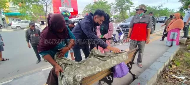 DI KURSI TROTOAR: Jenazah Kai Hadi ditutupi warga dengan sarung sebelum dievakuasi ke Rumah Sakit Ulin. | FOTO: MAULANA/RADAR BANJARMASIN