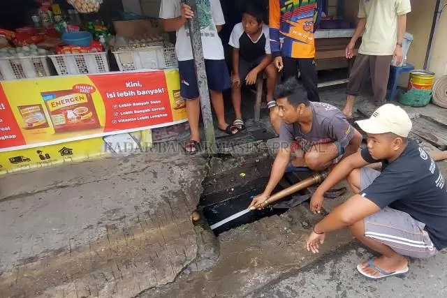 MAMPAT: Menggunakan selang dan mesin pompa milik relawan damkar, sumbatan drainase di Kelurahan Telawang disemprot dan didorong.