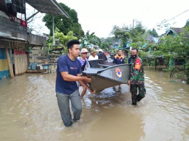 BANTU WARGA: Babinsa Koramil 1006-02/Pengaron bersama warga saat mengangkat perahu untuk mengevakuasi warga terdampak banjir di Pengaron, kemarin. | FOTO: KODIM 1006/BANJAR