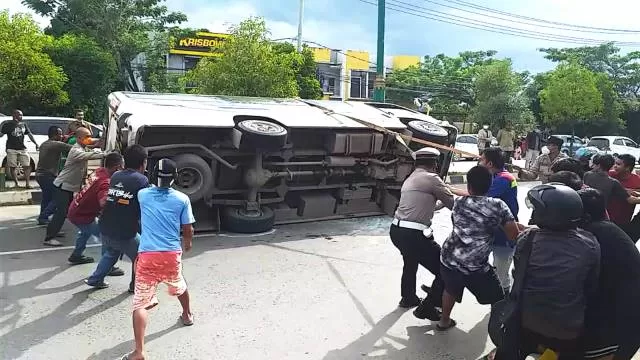 EVAKUASI: Warga dan polantas bahu-membahu mengevakuasi minibus yang terbalik di Jalan PHM Noor, Tanjung, kemarin (28/12).