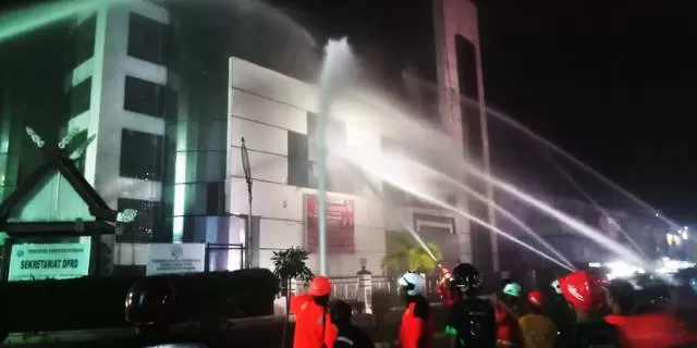 PEMADAMAN: Relawan damkar Kotabaru berjibaku menyemprot gedung DPRD di seberang kawasan wisata siring.