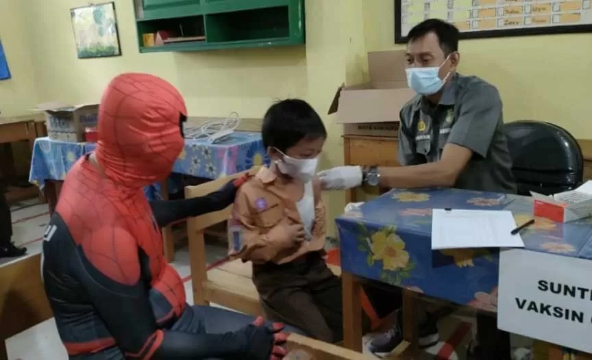 CARA UNIK: Anggota DPRD Banjarbaru, Tarmidi mengenakan kostum superhero Spiderman (kiri) untuk mendampingi anak-anak disuntik vaksin.