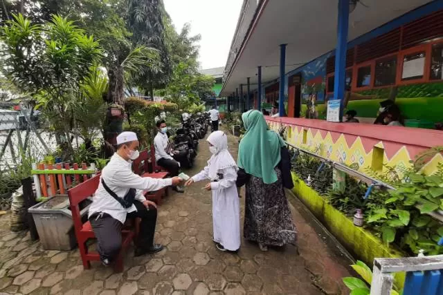 PROTOKOL: Guru mengukur suhu pelajar sebelum memasuki kelas selama PTM di Banjarmasin. | FOTO; WAHYU RAMADHAN/RADAR BANJARMASIN