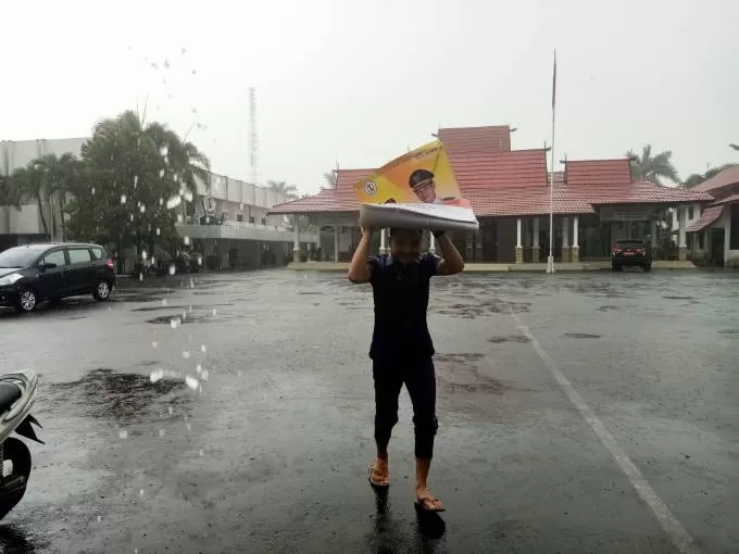 HUJAN MENDADAK: Seorang warga Marabahan berlindung dari hujan yang turun tiba-tiba. Sebelumnya Kalsel dilanda cuaca panas seperti banyak daerah lain di Indonesia. | FOTO: AHMAD MUBARAK/RADAR BANJARMASIN
