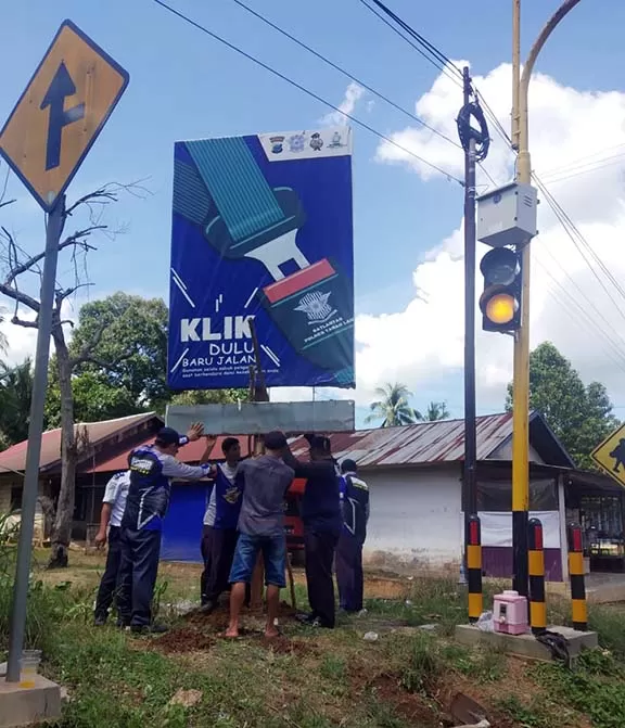 SIGAP: Petugas dari Dishub Tala memindah papan reklame yang menutupi rambu-rambu lalu lintas.
