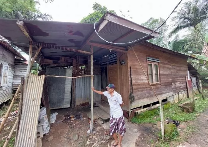 RUMAH SAYUTI: Ketua RT 6 Desa Benawa Tengah, Zainuddin di depan rumah tempat tinggal terduga pencuri kulit alis dan kelopak jenazah. FOTO: JAMALUDDIN/RADAR BANJARMASIN