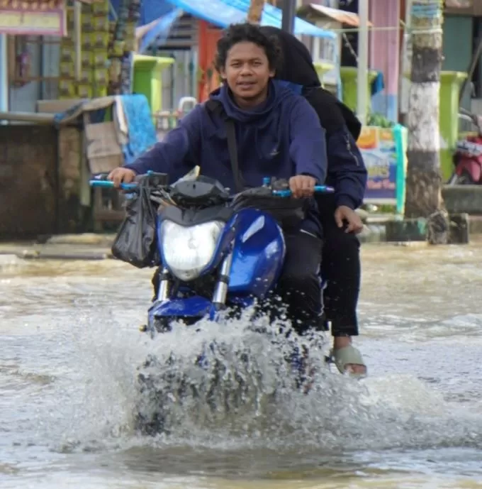 TEROBOS: Warga Barabai menerobos banjir dengan berjalan kaki atau bersepeda motor. Banyak motor yang kemogokan. | FOTO DAYAT FOR RADAR BANJARMASIN